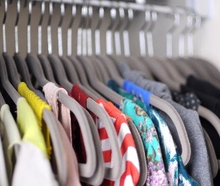 Image d’une garde-robe pleine de vêtements sur des cintres. 