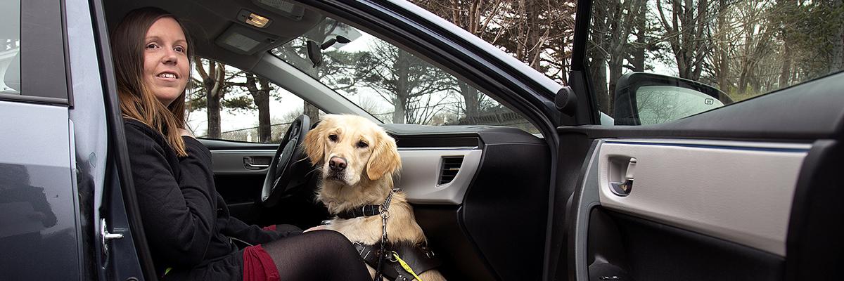 A woman and her Golden Retriever guide dog sitting in the passenger seat of a car.