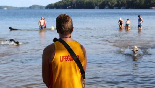 Two lifeguards enjoying summer fun on the beach with guests in a youth program.
