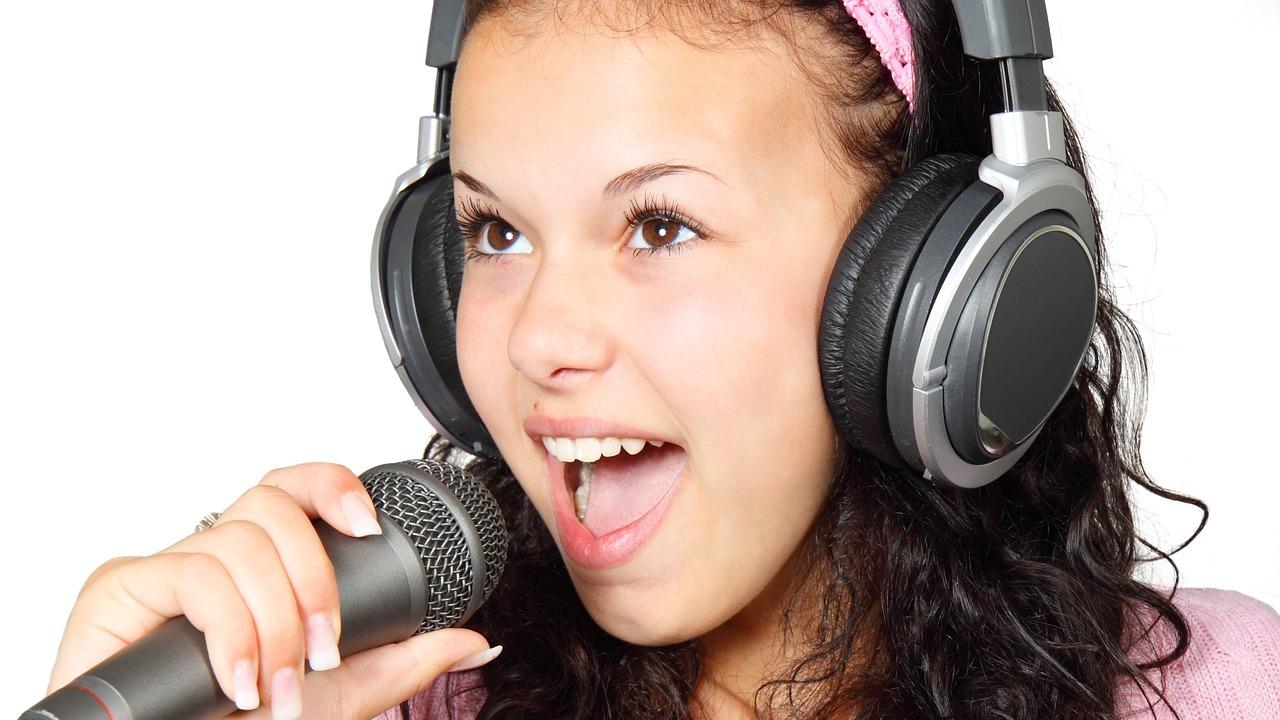 Young woman wearing headphones singing into a microphone
