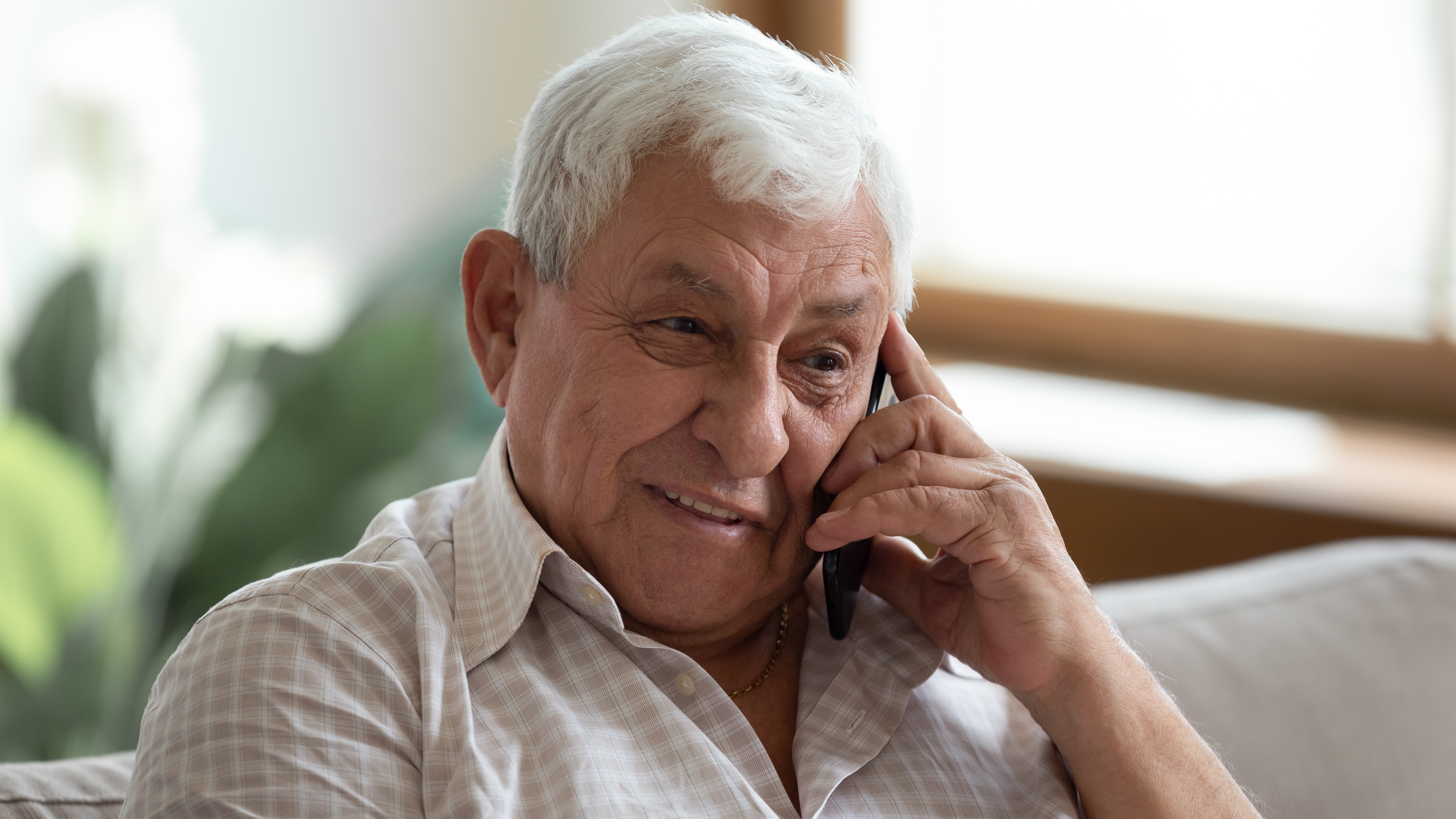 An elderly man talks on a smartphone.
