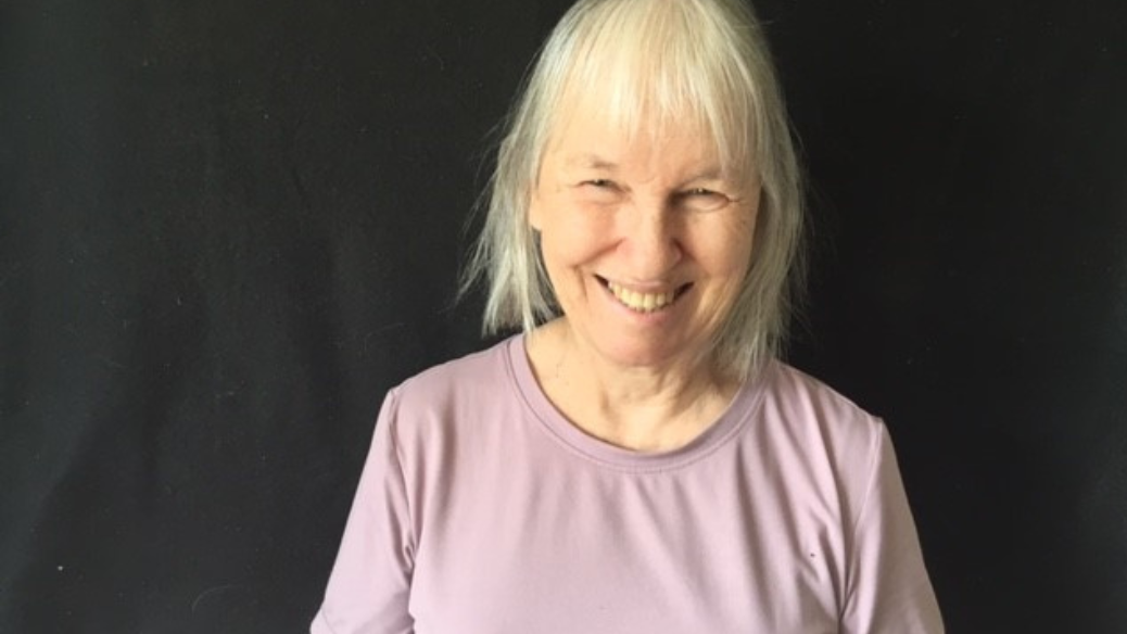 A headshot of Brenda Macalister smiling in front of a black background.