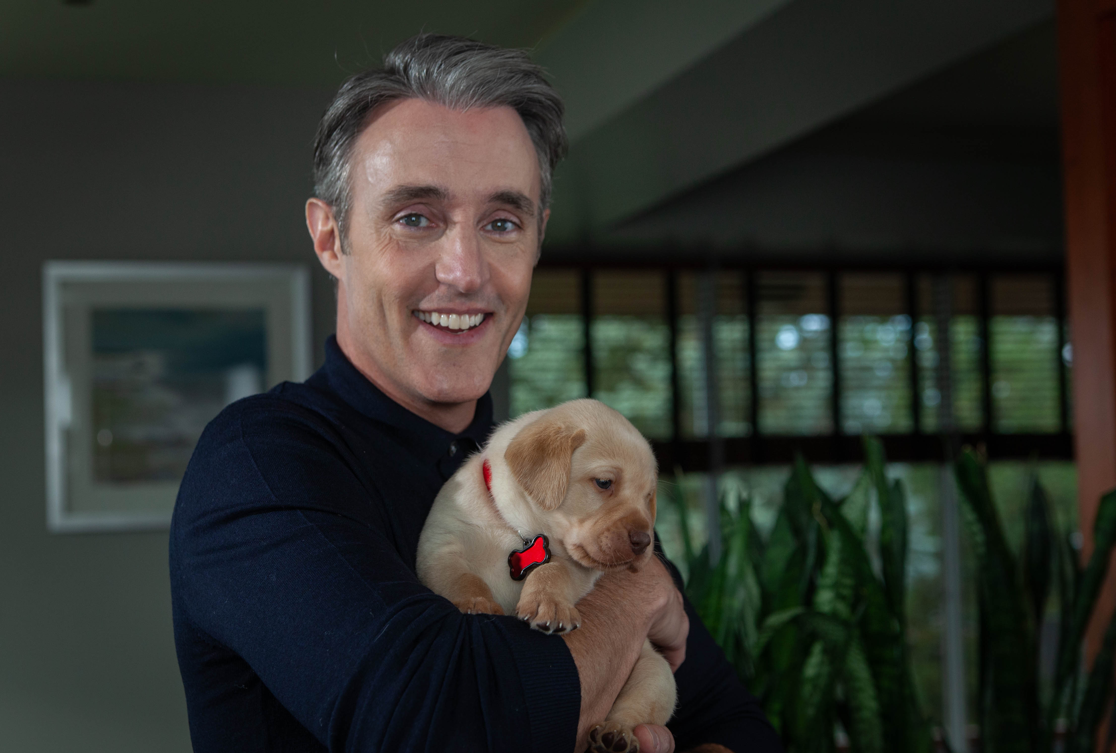 CNIB Ambassador Ben Mulroney holding a puppy