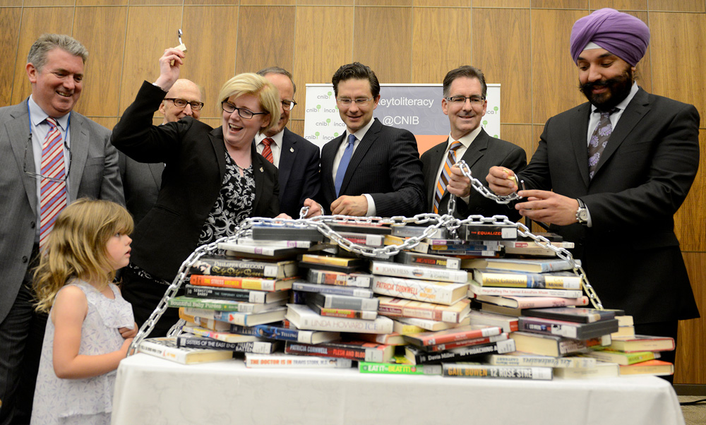 People celebrating over a pile of books on a table that have a chain over them, as if locked