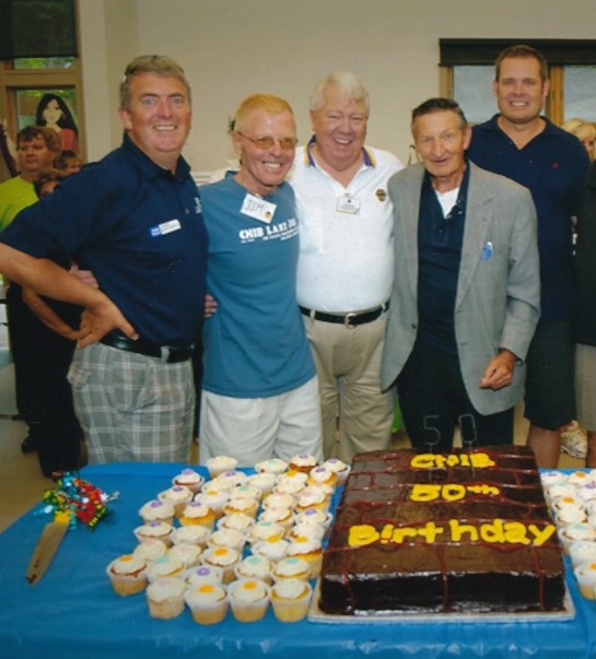 Photo de groupe réunissant John Rafferty, Jim Tokos, Carl Young, Walter Gretzy, Tim Tremain. Le groupe est debout derrière une table sur laquelle sont disposés des cupcakes.