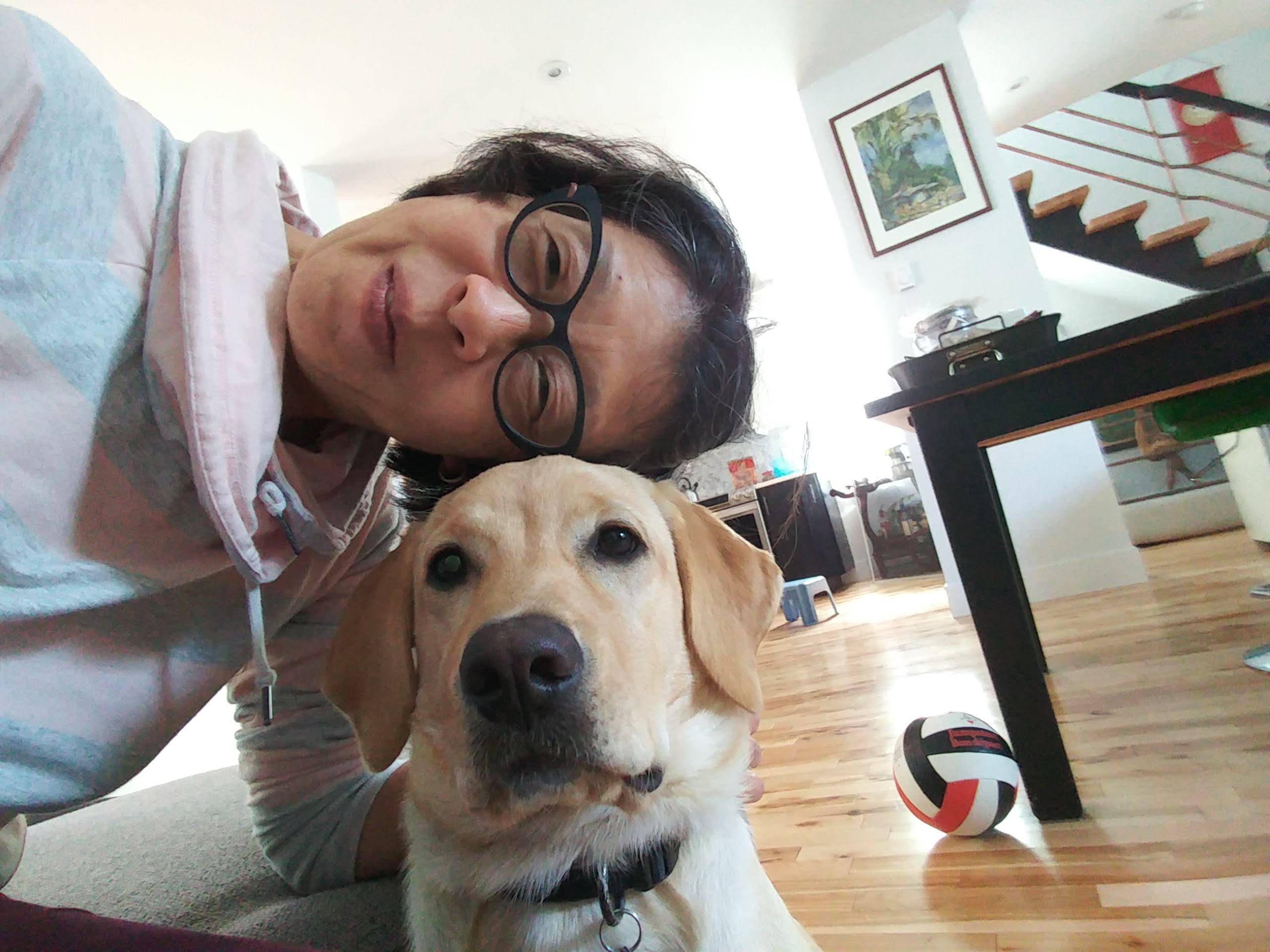 Yuko Imai sitting on the floor taking a selfie with Rhonda, a yellow Labrador-Golden Retriever cross.