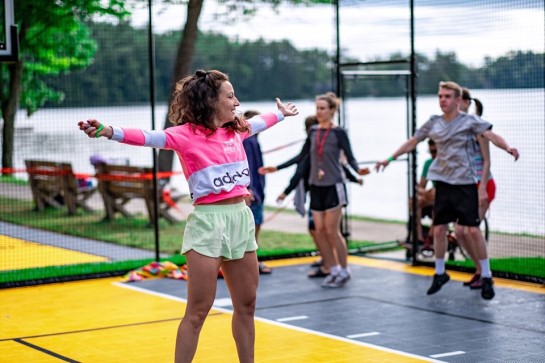 An outdoor fitness class featuring participants jumping around on the multi-sport court. 