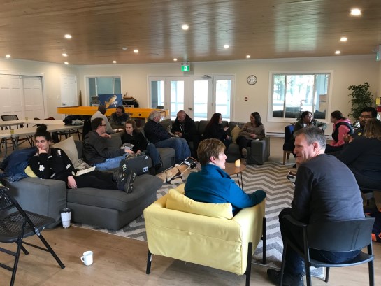 A photograph of members of the international learning retreat seated for discussion in the Rec Hall.