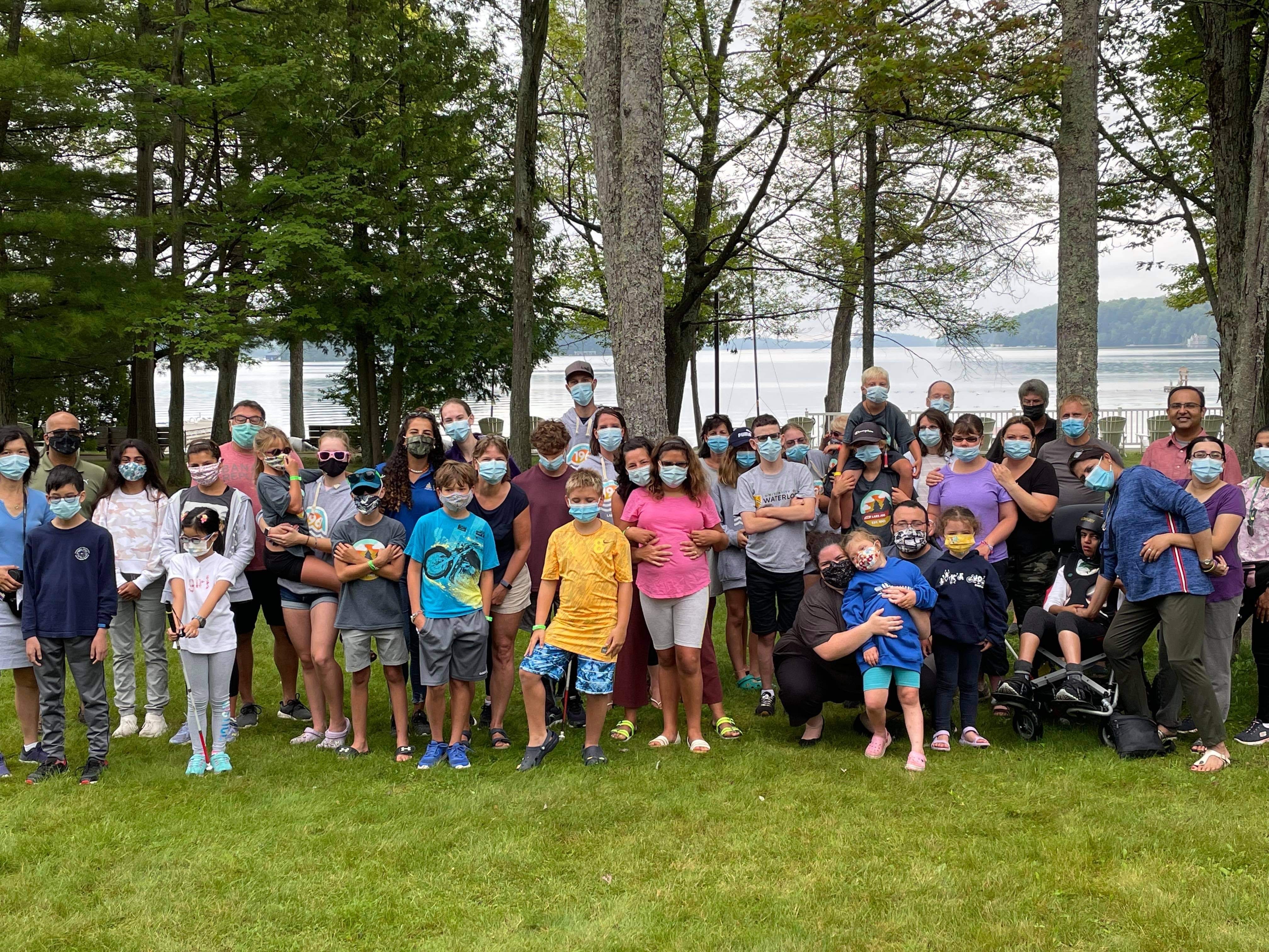 A large group of guests wearing face masks pose on the lawn at CNIB Lake Joe.