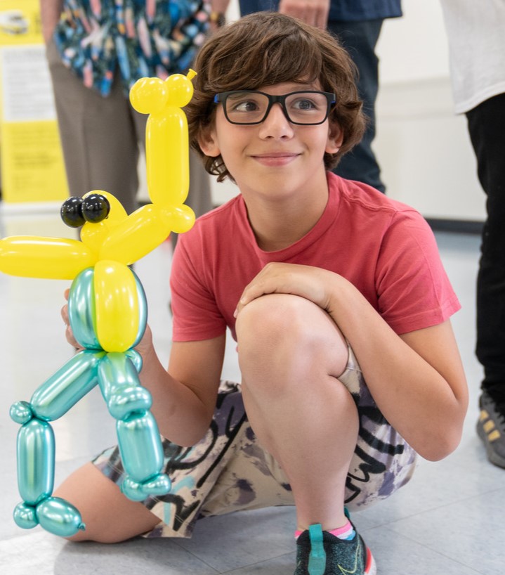 Gabriel, a CNIB Lake Joe camper, poses knelt down with a balloon animal.