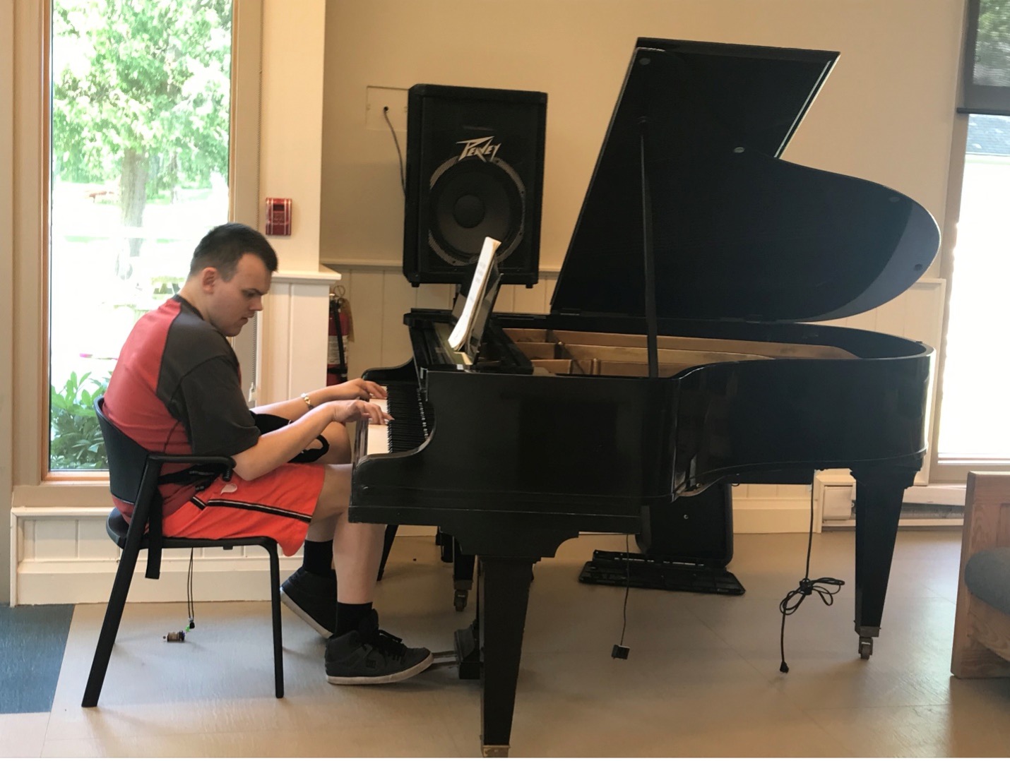 Daniel Kisielewski, guest at CNIB Lake Joe Adult Week 2022, playing the black grand piano in the CNIB Lake Joe lounge.