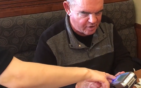 A server helps a man use an inaccessible point of sale terminal at a restaurant. 