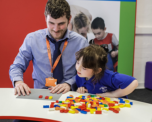 Un homme et un enfant jouent avec des briques LEGO en braille  
