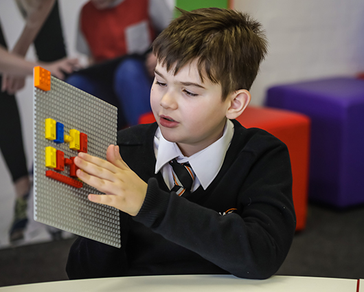 Un garçon joue avec des briques LEGO en braille  