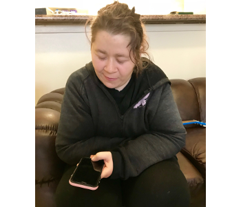 Crystal Gunn sits on a couch and holds her iPhone in her left hand