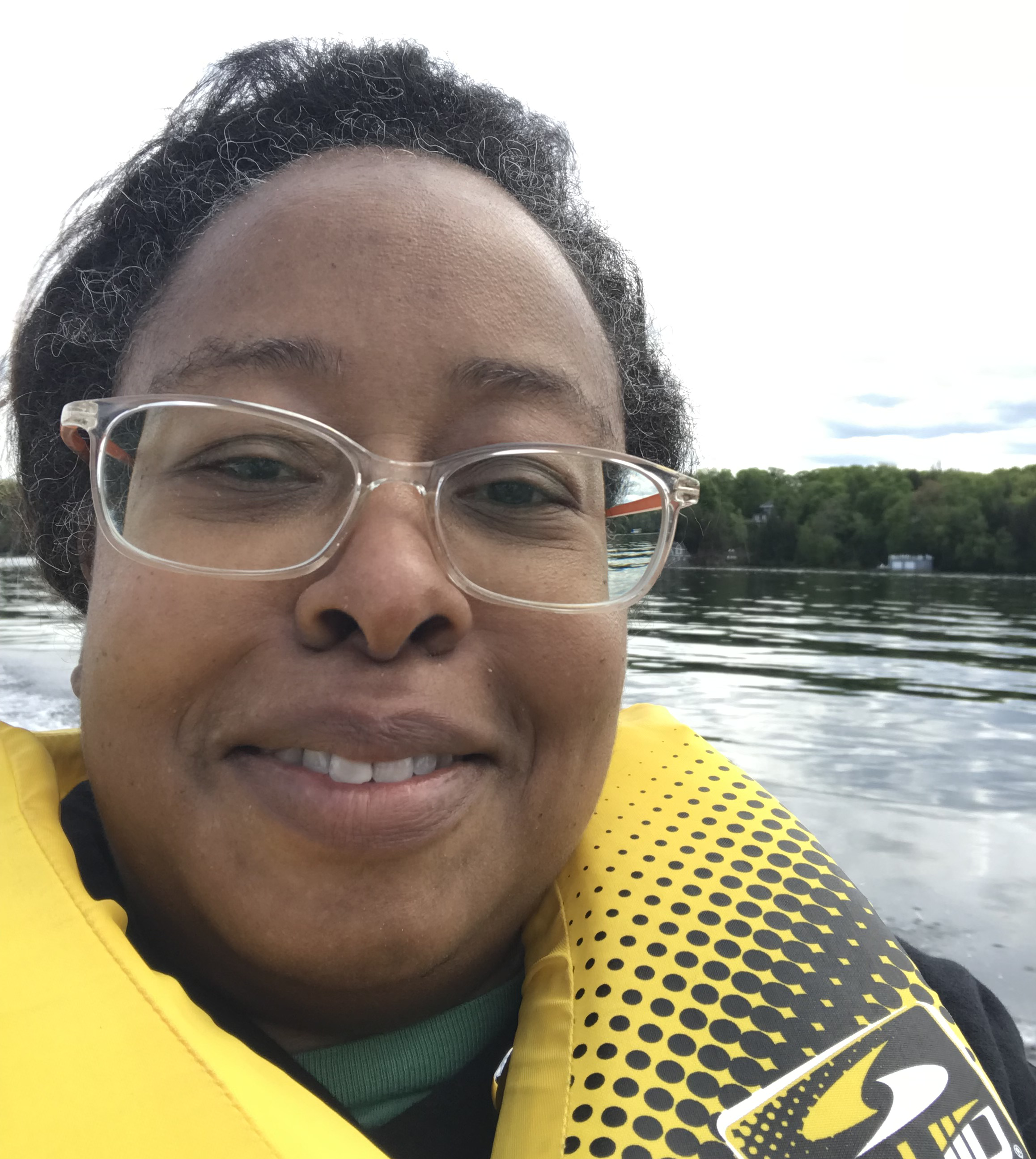 Llonella wears a yellow lifejacket and sits on a boat at CNIB Lake Joe.