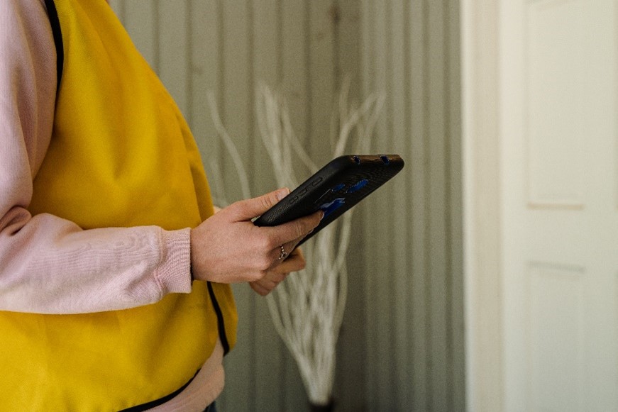 A close view of a CNIB Fundraiser’s yellow vest and fundraising tablet