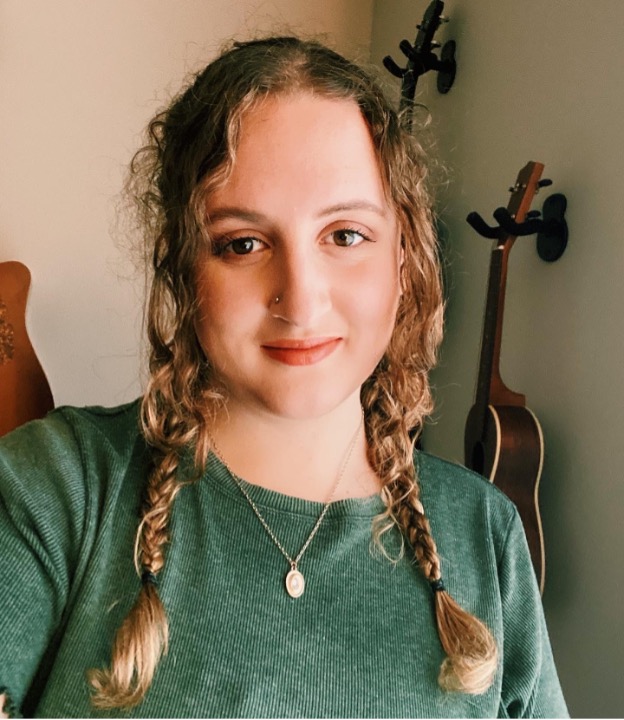 Taylor Gaudot is smiling for a photo wearing her hair in braids and a green top.