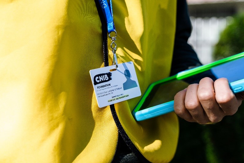 Vue rapprochée de la veste jaune, de l'insigne d'identité et de la tablette de collecte de fonds d'un collecteur de fonds d'INCA