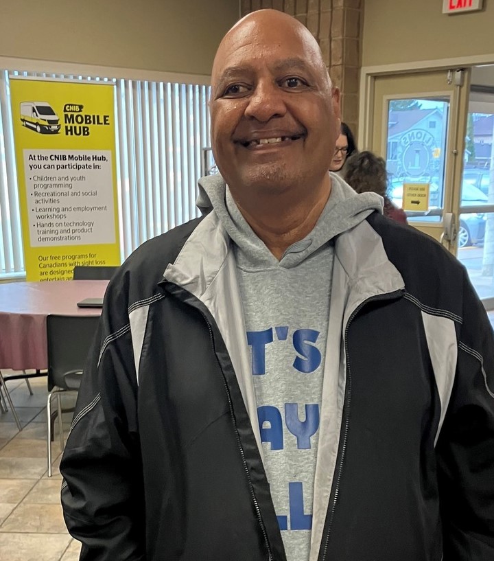 Wasif, a CNIB Mobile Hub participant, smiles at the camera. Wasif is wearing a grey hoodie, with a black jacket over top.