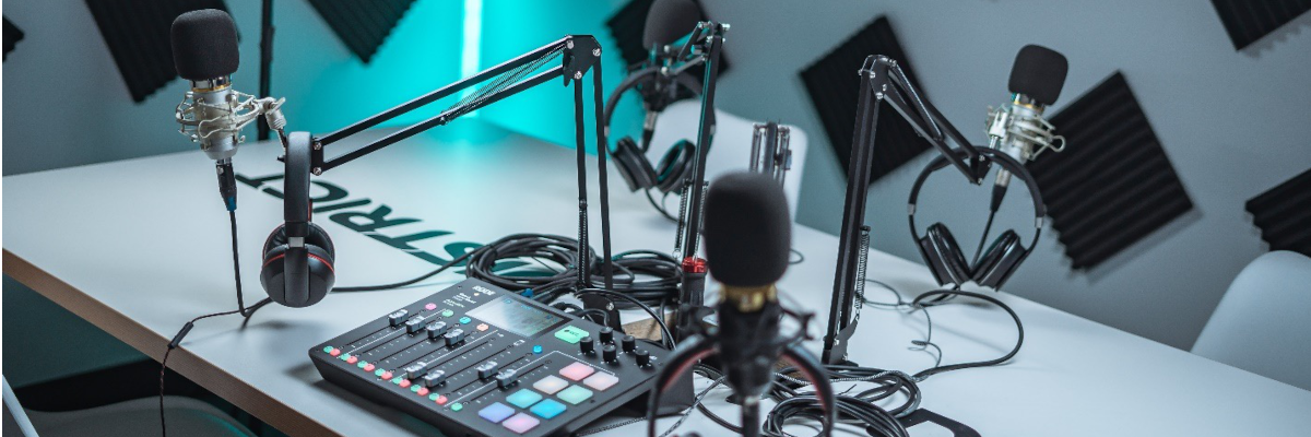 A desk with podcast equipment on top (microphones, headphones, cables, mixer)