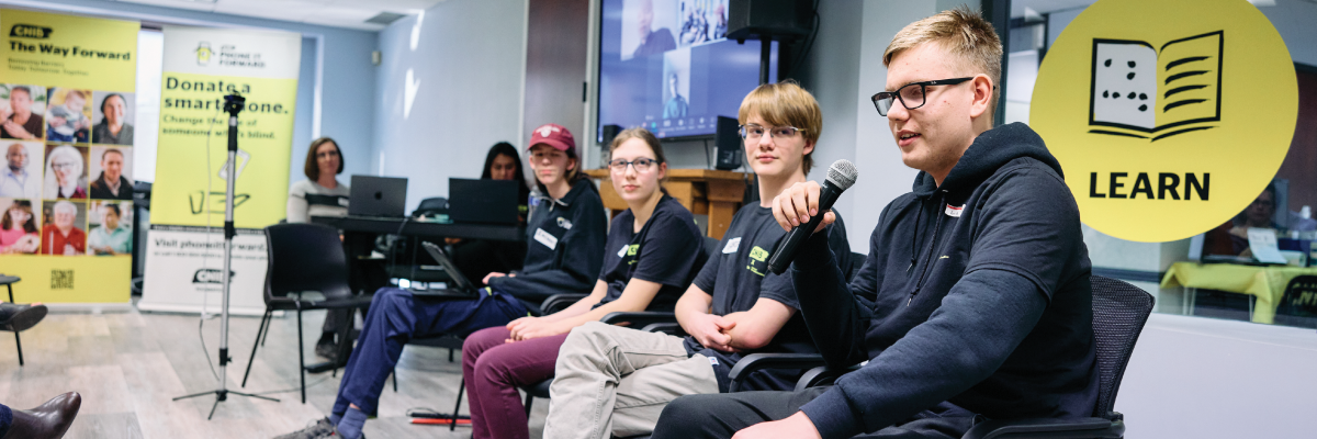 Un panel de quatre jeunes est assis en ligne à l'avant de la pièce dans le bureau d'INCA en Calgary. 