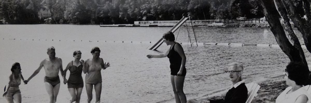 Ancienne photo en noir et blanc de campeurs sur les rives et la plage du lac en 1961