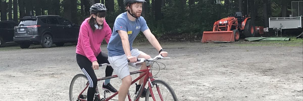 Two young adults tandem cycle at CNIB Lake Joe.