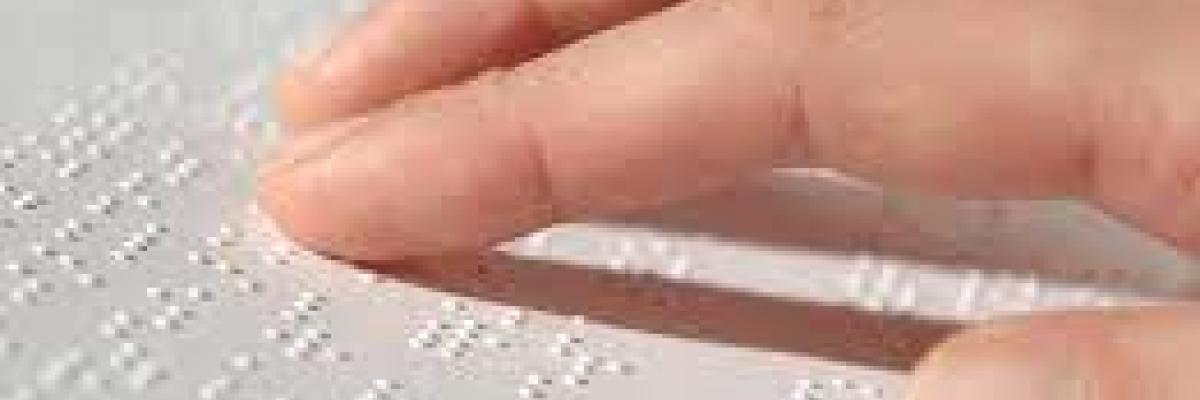 Photo d'une main se déplaçant sur du papier braille.
