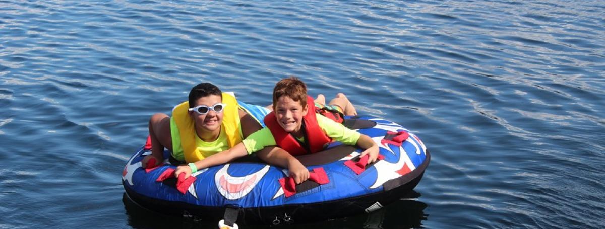 Two boys on Lake Joseph in an inner tube, ready to be pulled.