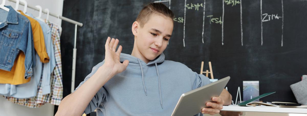 Un jeune fait un salut devant une tablette.