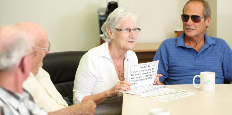 A peer support group. Four people engage in conversation around a table.