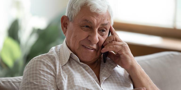 An elderly gentleman talks on a smartphone.