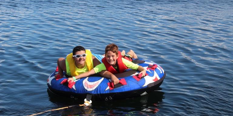 Two boys on Lake Joseph in an inner tube, ready to be pulled.