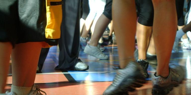 Feet move about during a dance class on a gymnasium floor.