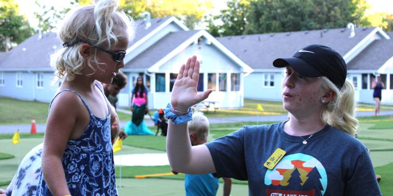 Staff member with a young girl giving her a high five.