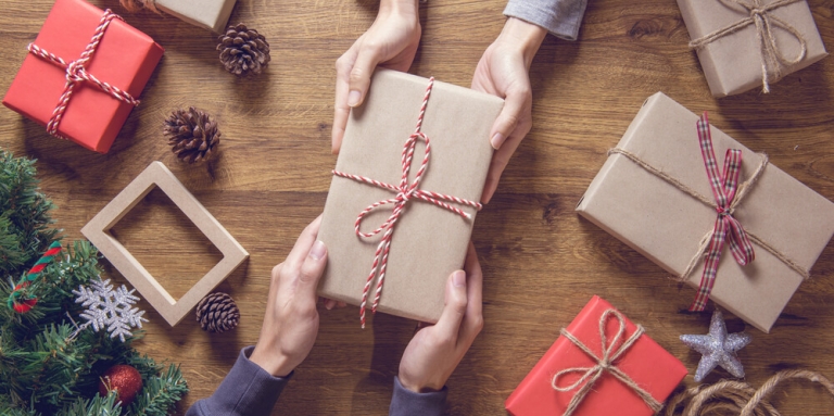 bird's eye view of wrapped gifts on a table with people handing boxes to each other