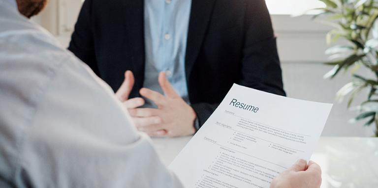 A recruiter holds a resume and interviews a candidate. 