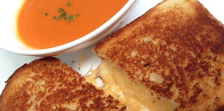 Grilled cheese sandwich next to a bowl of soup