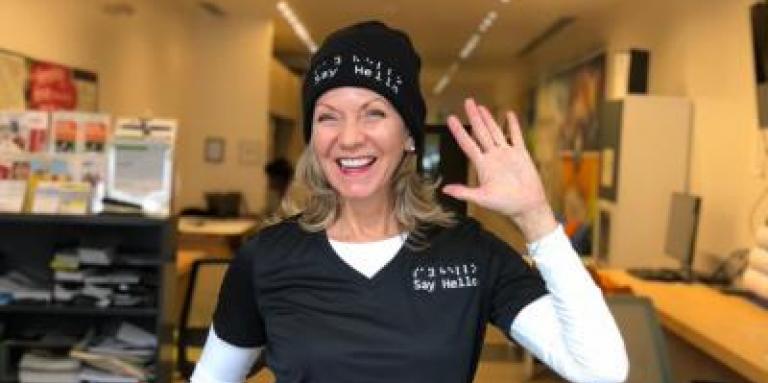 Denise Justin, fondatrice de “Say Hello 2 Blindness” sourit en saluant de la main. Elle se trouve au Carrefour communautaire d’INCA à Toronto.
