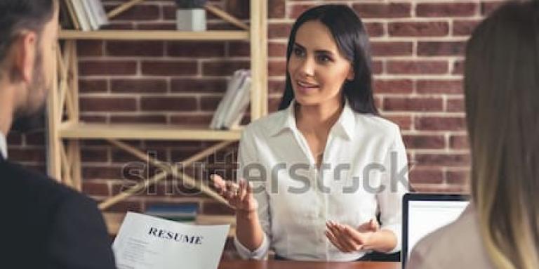 Jeune femme assise face à deux personnes qui lui posent des questions lors qu'un entretien d'embauche