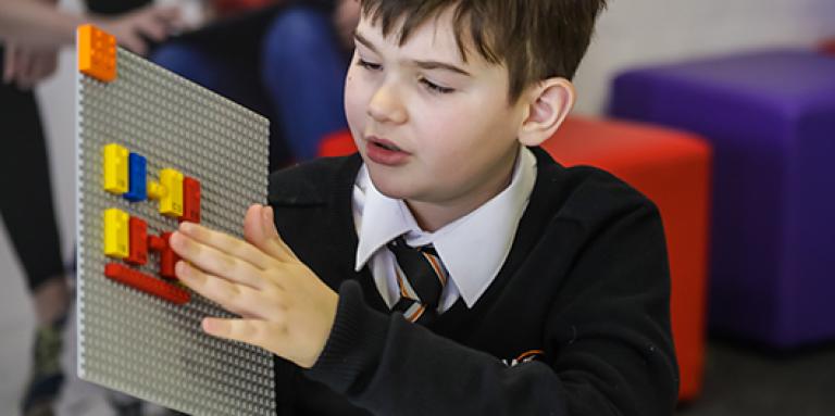 Boy who is blind touches LEGO Braille Bricks