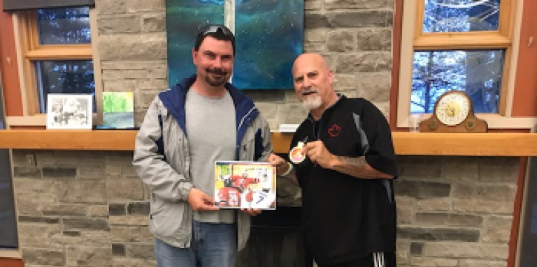 Guy Carriere & his guide dog (left) and Paul Rosen (right) pose for a photo together. Guy is holding an autographed picture of Paul and Paul is displaying a medal in his left hand. 