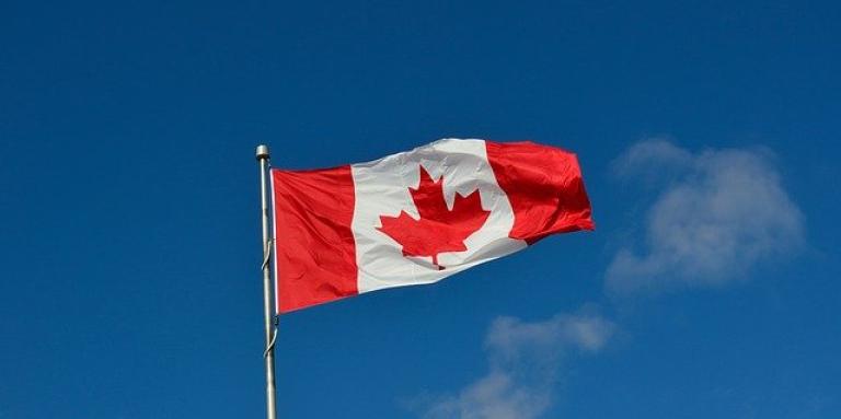 A Canadian flag waves in a clear, blue sky.