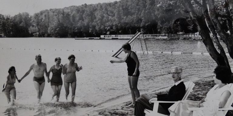 Ancienne photo en noir et blanc de campeurs sur les rives et la plage du lac en 1961