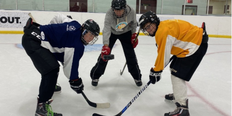 Une mise au jeu. Les joueurs de hockey Brayden, Mathew et Eli s'entraînent sur la patinoire. 