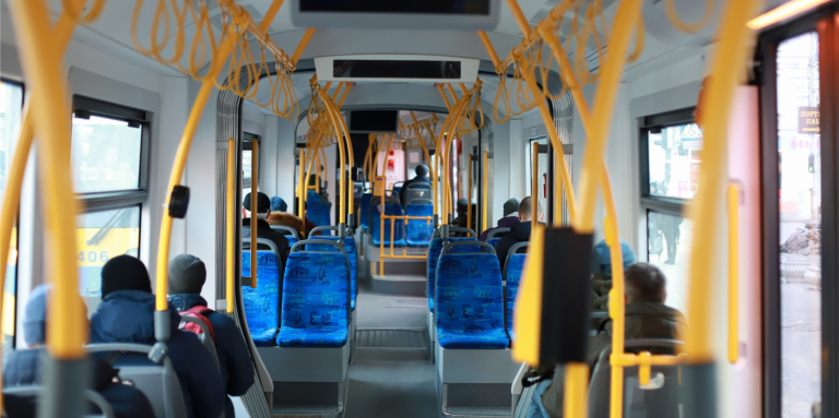 L’intérieur d’un autobus urbain avec des passagers assis. L’image est prise de l’arrière de l’autobus. 