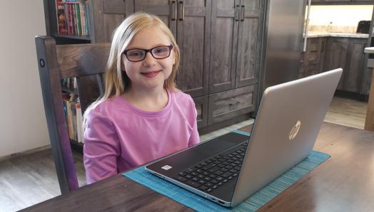 Madelyn sits in front of her laptop and smiles.