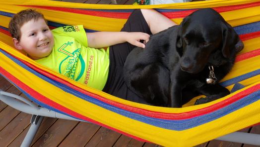 Ollie and Hope laying in a colourful hammock, cuddled up together and smiling