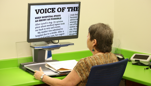  A woman sits at a CCTV and reads an enlarged document displayed on the screen.